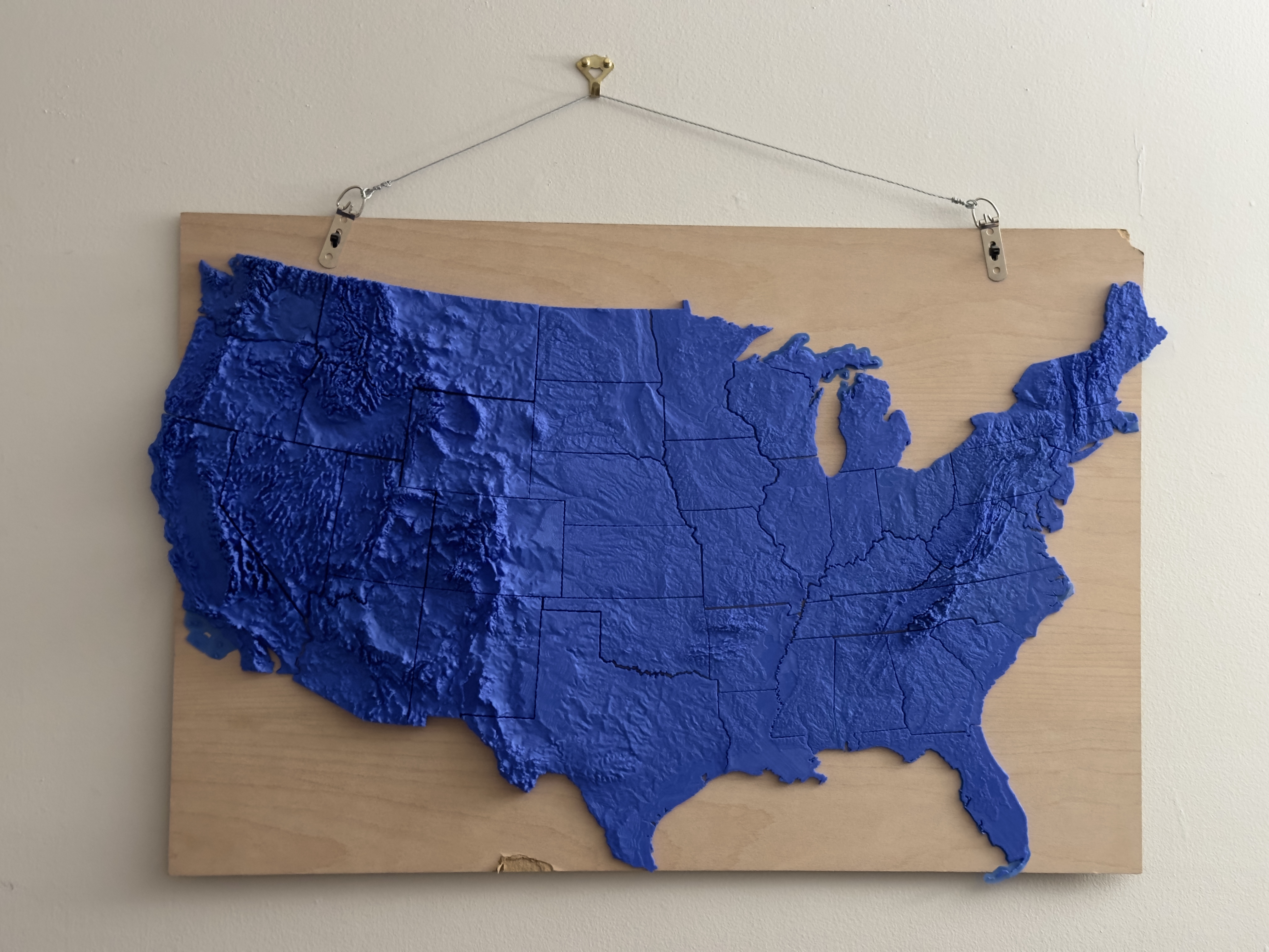 A 3D printed topographical map of the United States, in blue plastic.